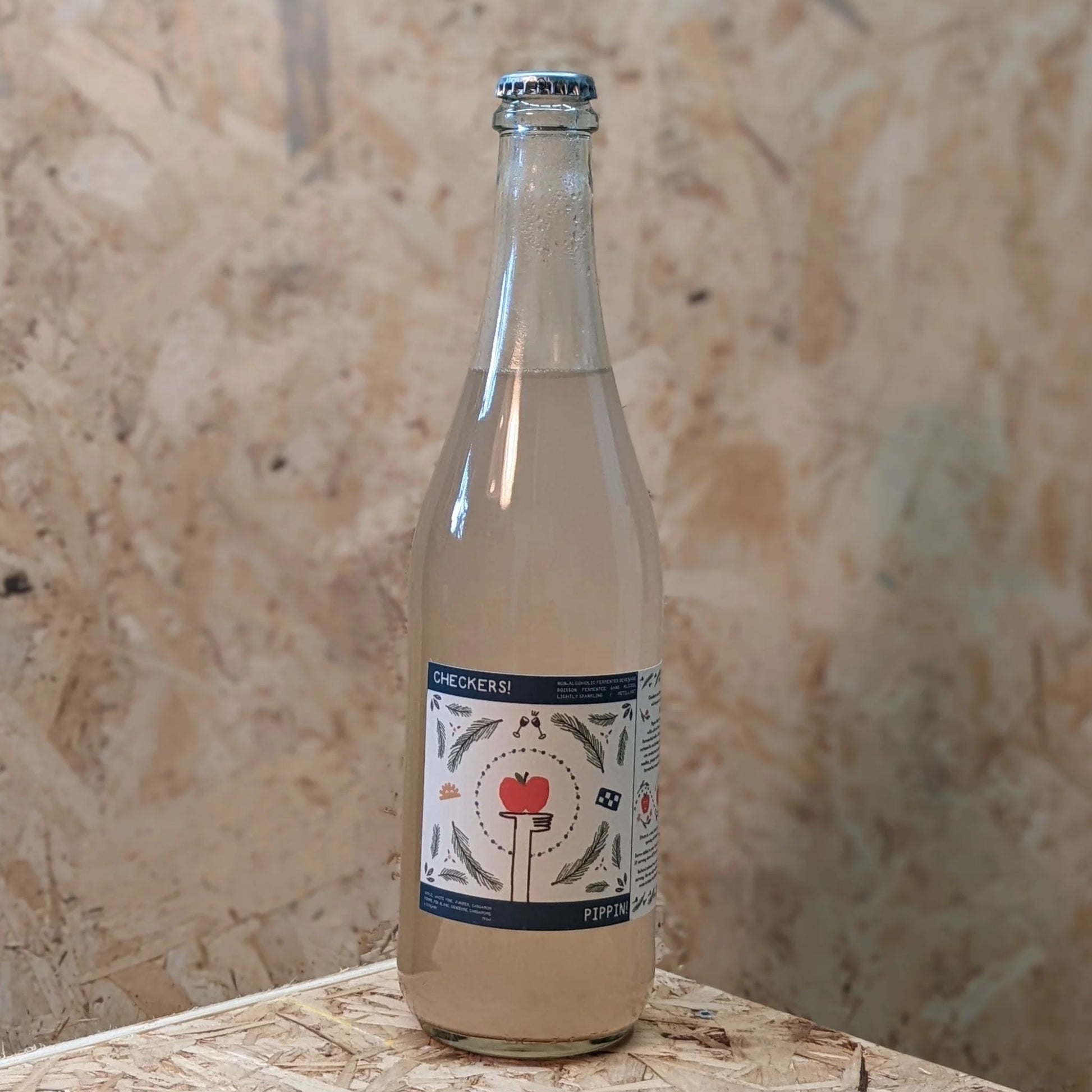 A clear glass bottle of Checkers! Pippin drink with a light liquid, featuring a label with an apple graphic and text.