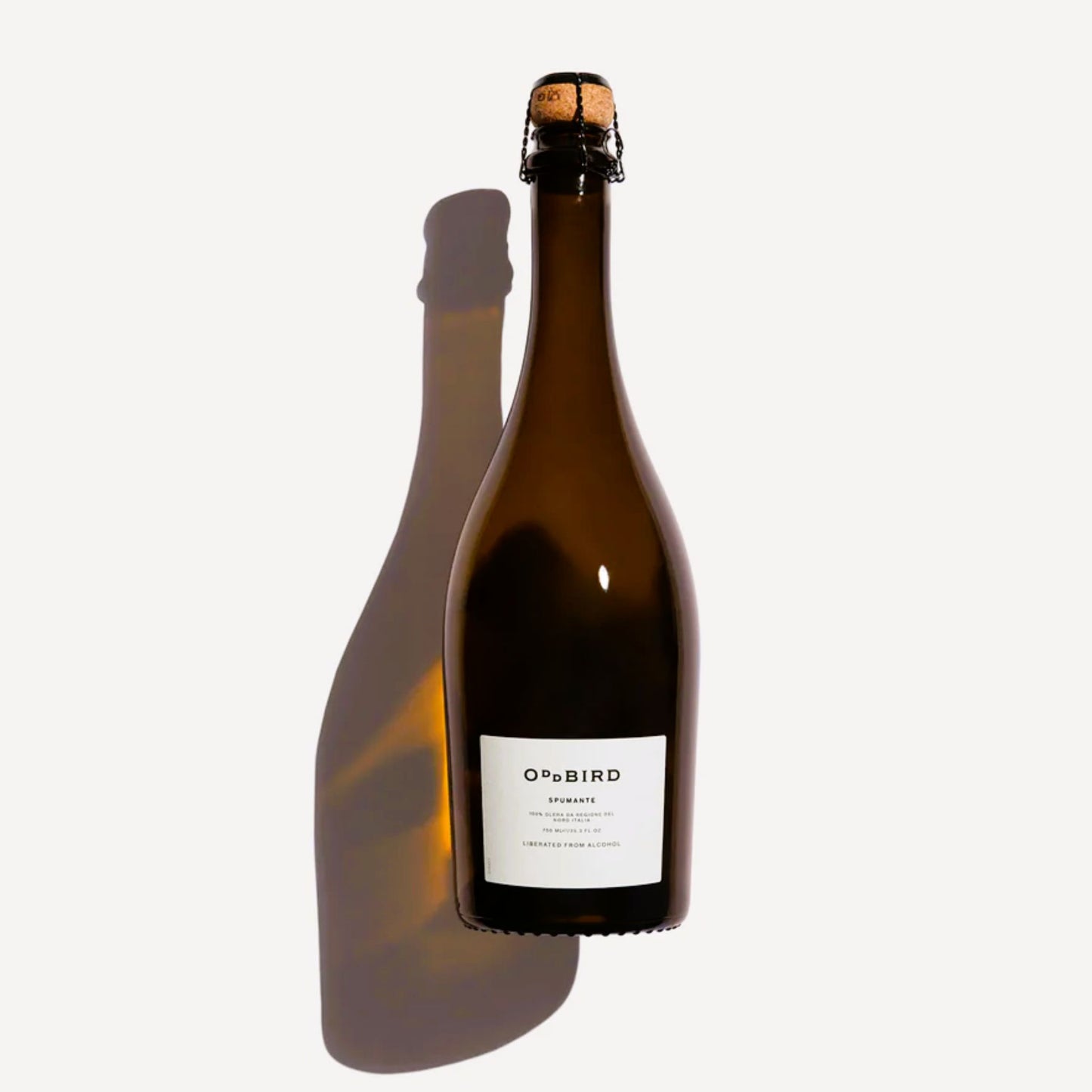 Bottle of Oddbird Spumante; a premium non-alcoholic sparkling wine from the Treviso region of Italy. The dark bottle protects the liquid, sealed with a traditional cork and cage. Recognized as the best alcohol-free Prosecco alternative, it is crafted from 100% Glera grapes and matured for 12 months before dealcoholization, offering a sophisticated palate of white pear, green apple, and elderflower. Made in French by a women-owned company. Available at Knyota Drinks in Ottawa.