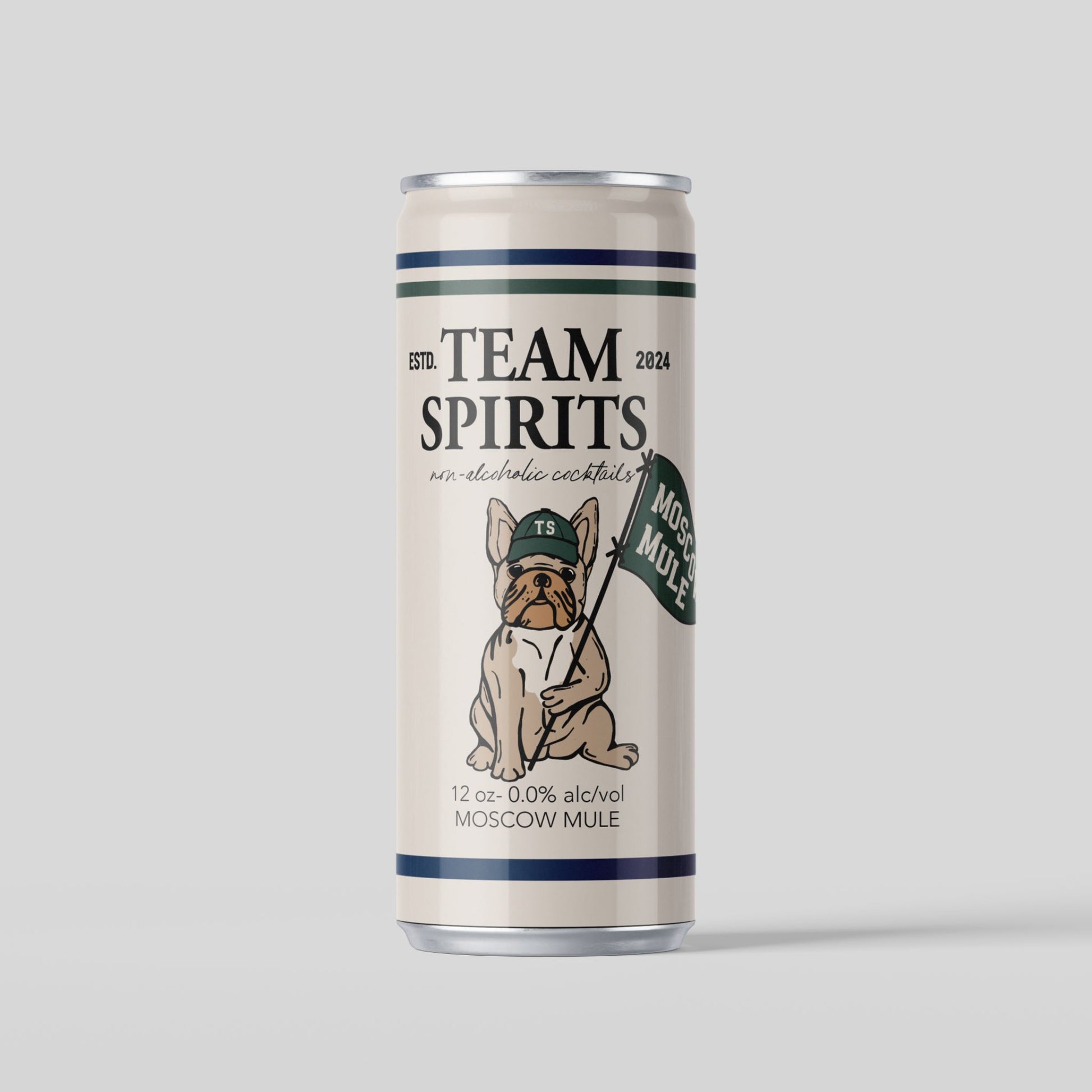 A cream-colored can of Team Spirits non-alcoholic Moscow Mule. The can has dark blue and green horizontal stripes at the top and bottom. The center of the can features an illustration of a bulldog wearing a green baseball cap and holding a flag that says "MOSCOW MULE". The text "TEAM SPIRITS" is at the top of the can, with "non-alcoholic cocktails" below it. The can also specifies "12 oz - 0.0% alc/vol" and "MOSCOW MULE" at the bottom. The background is a solid light gray.