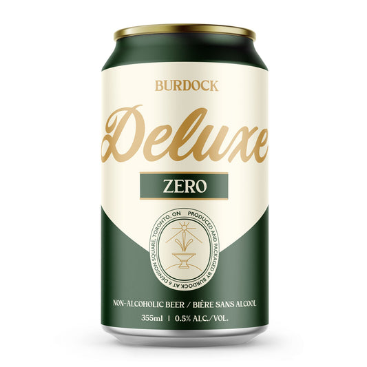 A beverage can from Burdock, primarily dark green at the top and bottom, with a cream-colored middle section. The word "BURDOCK" is printed in black at the top of the cream section. Below that, "Deluxe" is written in a large, elegant dark green script. Centered beneath "Deluxe" is a small green rectangle with "ZERO 5" in white text. The bottom green section of the can features text wrapped around a circular logo, including "NON-ALCOHOLIC BEER / BIÈRE SANS ALCOOL" and "355ml | 0.5% ALC./VOL.".