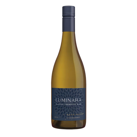 A high-quality product image of the 2023 Luminara Alcohol-Removed Chardonnay. The clear glass wine bottle showcases the wine's light gold/yellow hue and features a striking navy blue label with a golden, patterned design, stating "Luminara Alcohol-Removed Wine," "Napa Valley," and "Chardonnay." The bottle is sealed with a dark blue foil screw cap, marketing a premium non-alcoholic white wine for zero-proof enthusiasts.