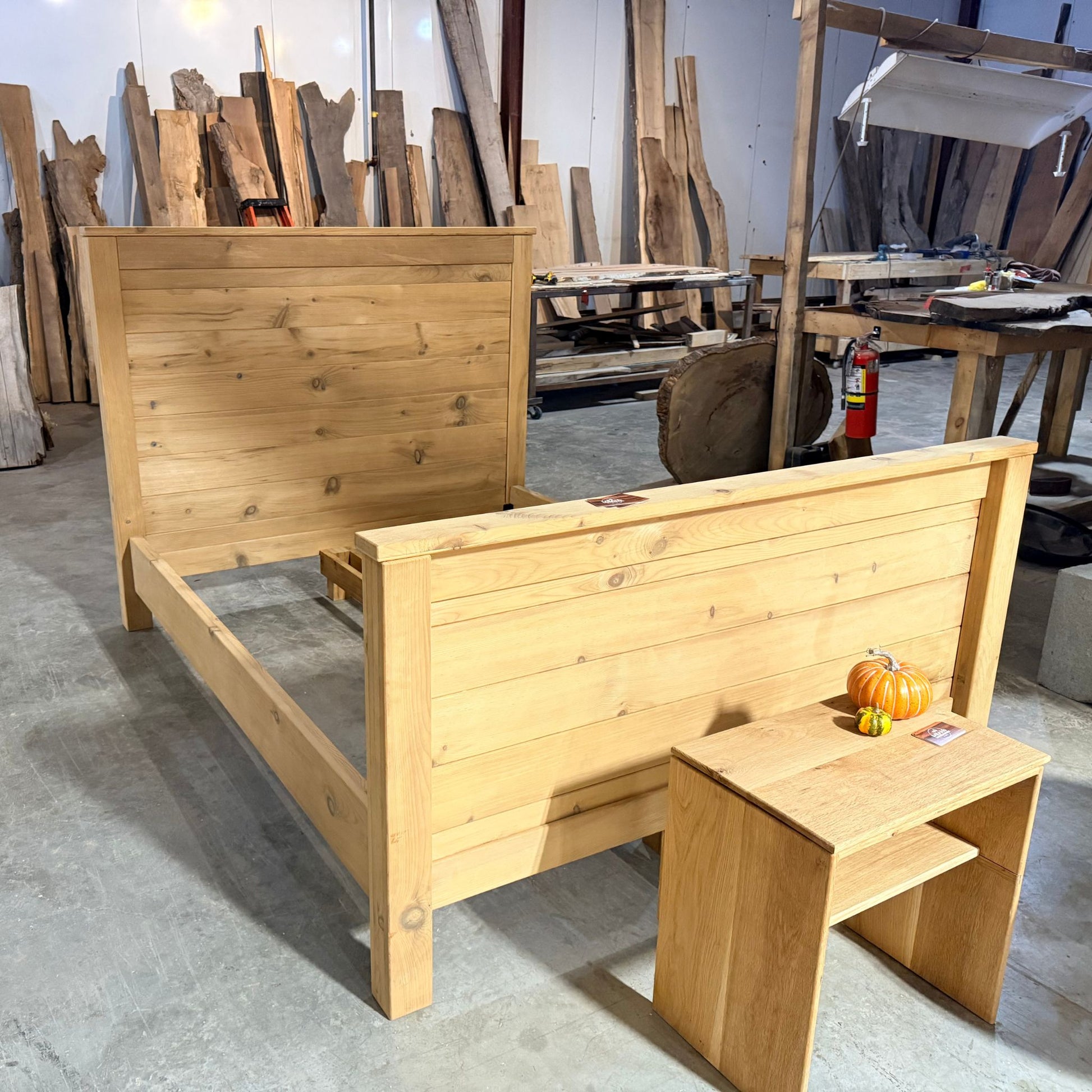 Handcrafted king size bed frame made from torrefied pine with matte finish, shown in a woodworking studio by Milano Woodworking