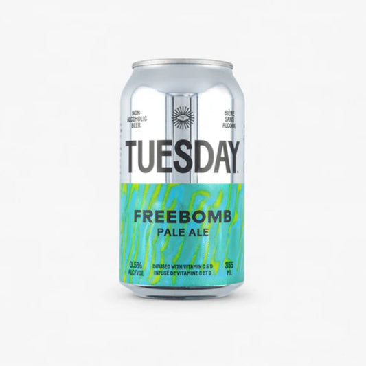 The image shows a silver can of Tuesday Freebomb Non-Alcoholic Pale Ale. The can has a black label with the brand name "Tuesday" in large white letters. The can is labeled as non-alcoholic beer with 0.5% alcohol by volume. It is also infused with vitamins C and D.