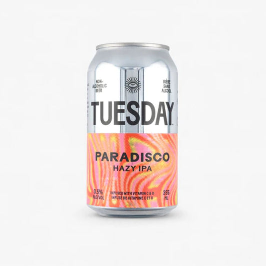 The image shows a silver can of Tuesday Paradisco Non-Alcoholic Hazy IPA. The can has a black label with the brand name "Tuesday" in large white letters. The can is labeled as non-alcoholic beer with 0.5% alcohol by volume. It is also infused with vitamins C and D.