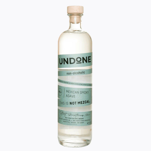 A clear, high-resolution product shot of a corked glass bottle of UNDONE non-alcoholic Mexican Smoky Agave (No. 4, 700ml) against a white background. The transparent spirit is visible inside. The label, featuring a soft teal/mint green and white design, clearly states "UNDONE," "non-alcoholic," and "MEXICAN SMOKY AGAVE" with the tagline "THIS IS NOT MEZCAL." This image is optimized for users searching for non-alcoholic tequila alternatives, alcohol-free agave spirits, or smoky zero-proof mezcal substitutes.