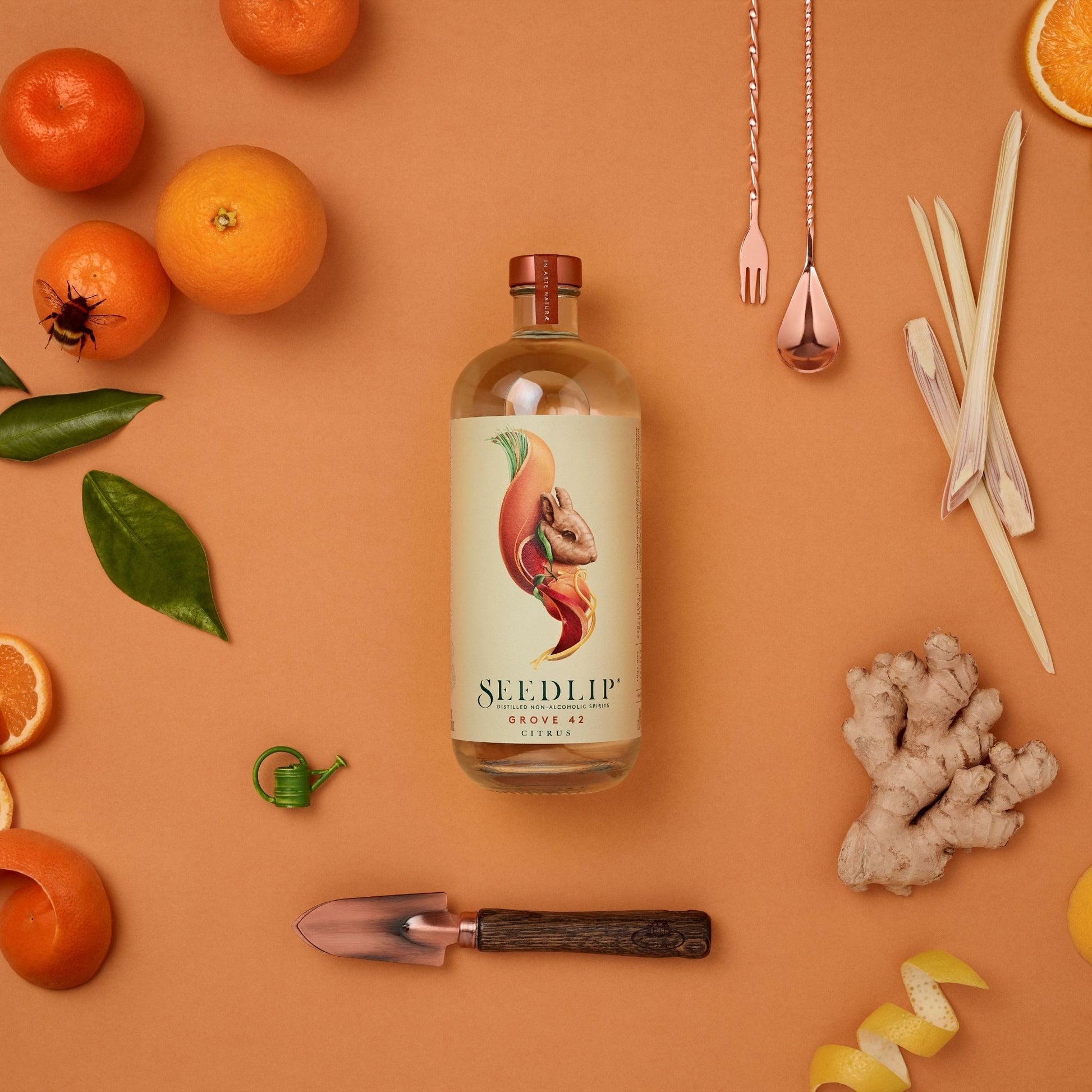 A photo of a 700 milliliter bottle of Seedlip Grove 42 Citrus surrounded by herbs, fruits, and bar tools.  Seedlip is available for sale at knyota.com